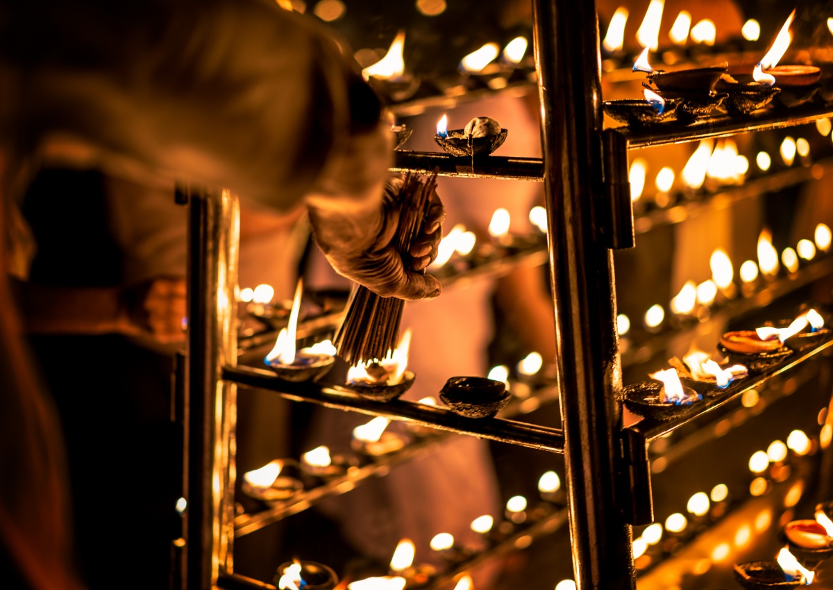 Photo of hundreds of candles and an old man lighting up incense