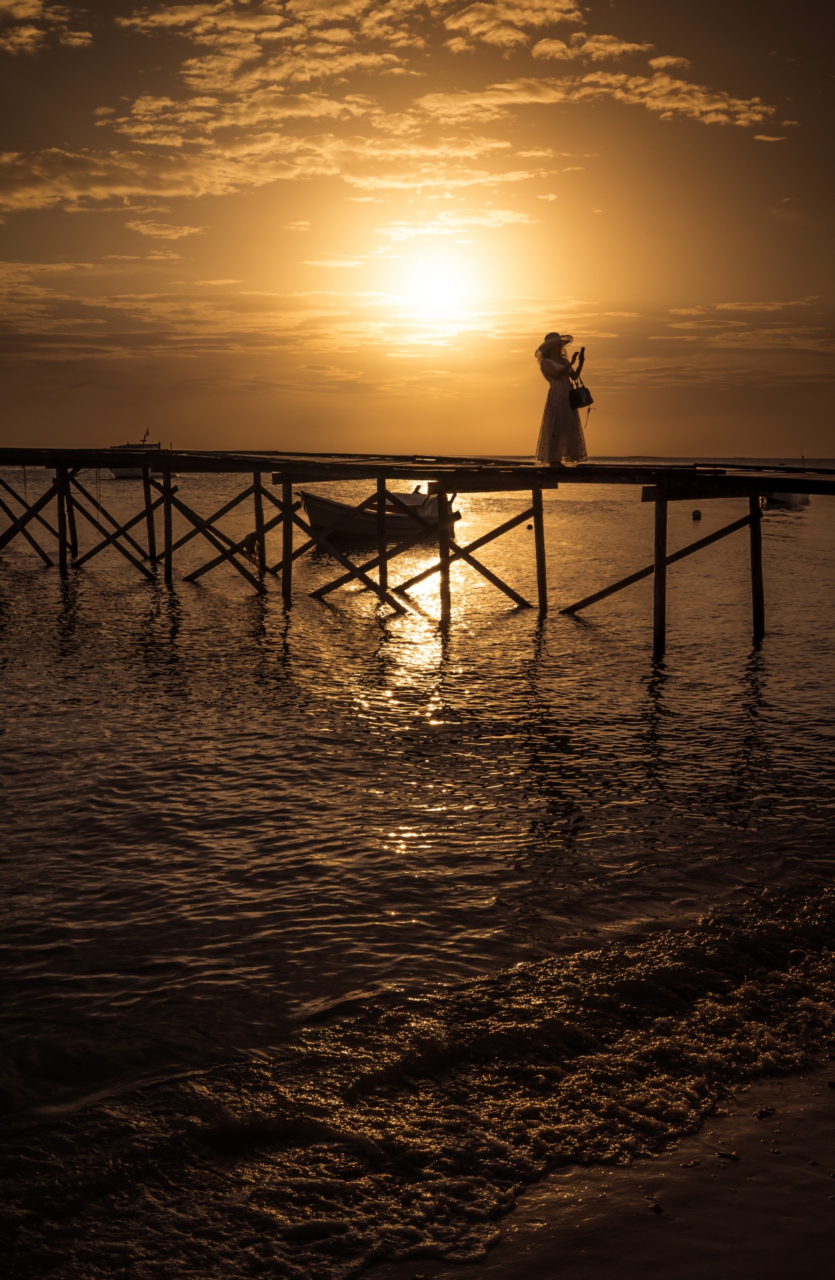 Photo of sunset over pier while picturisque lady is taking a selfie