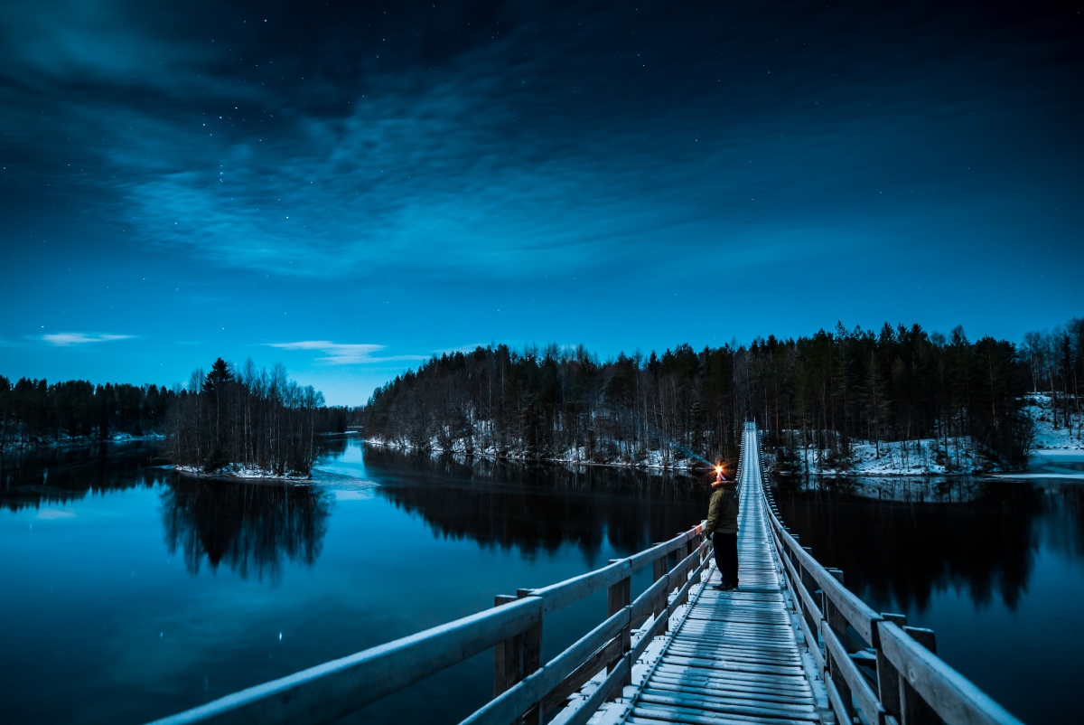 Night view with stars over suspension bridge over frozen river Oulujoki in Finland